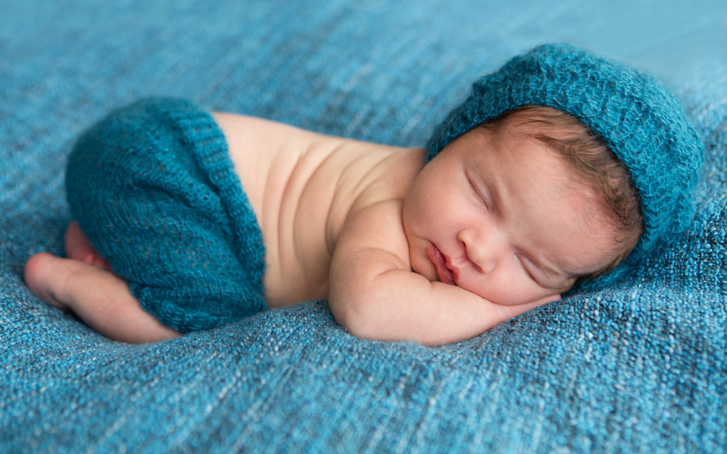 Спящий грудной ребенок лежит на голубом покрывале 