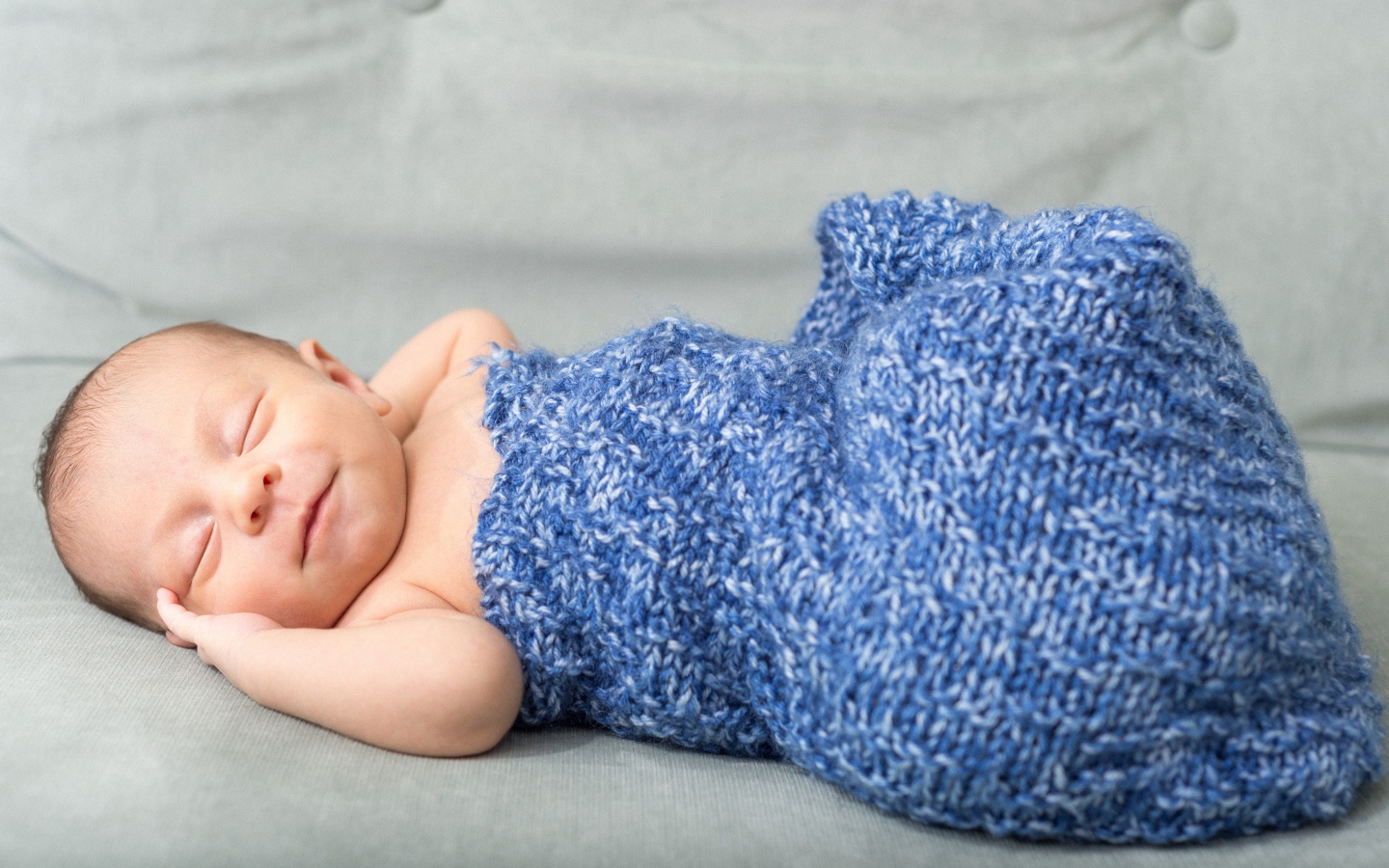 Маленький грудной ребенок в синем вязаном покрывале 