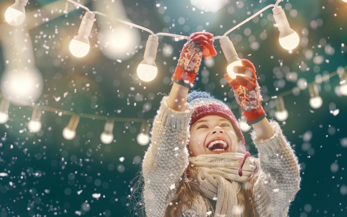 Улыбающаяся девочка вешает лампочки 