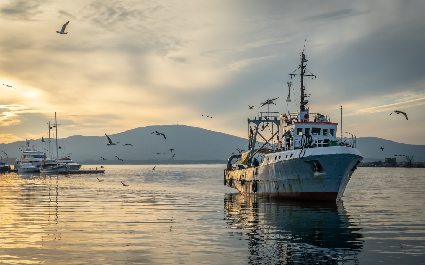 Старое рыболовное судно в море на закате 