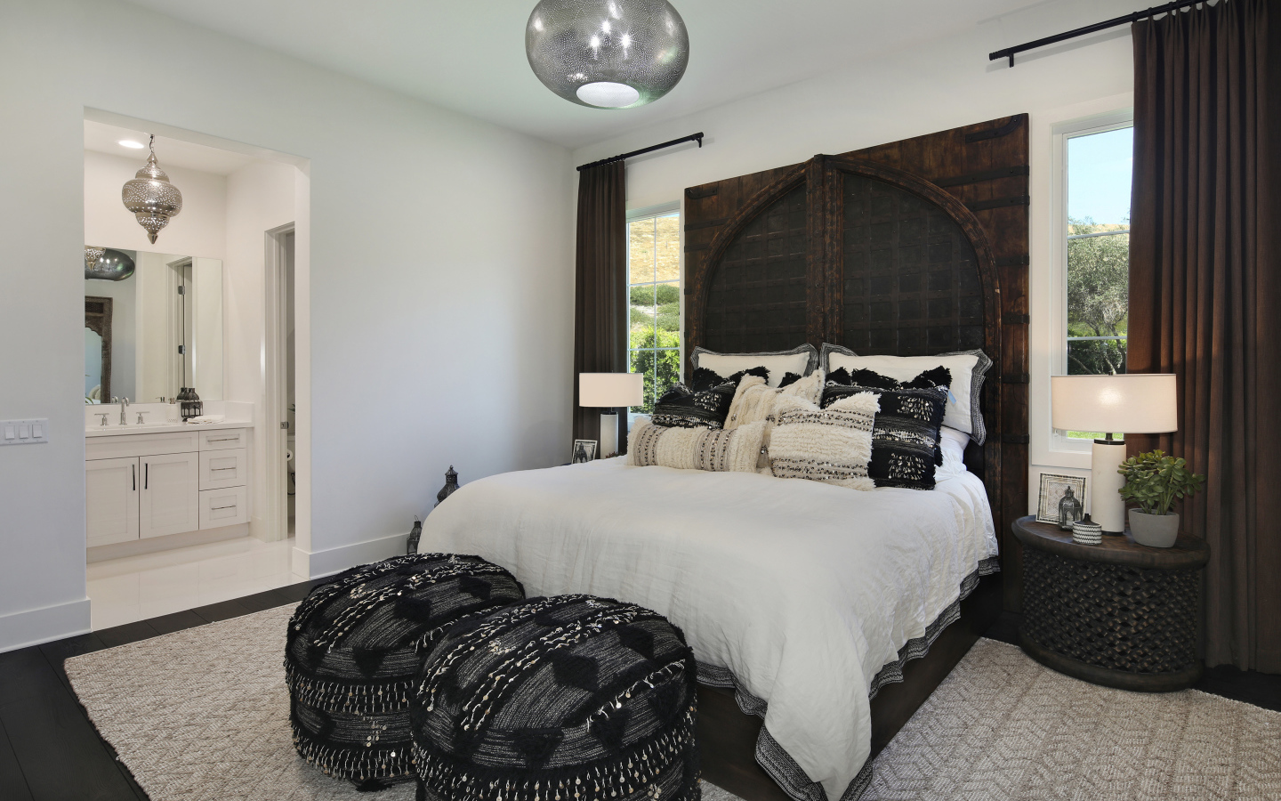 Большая кровать в спальне с большими окнами со шторами