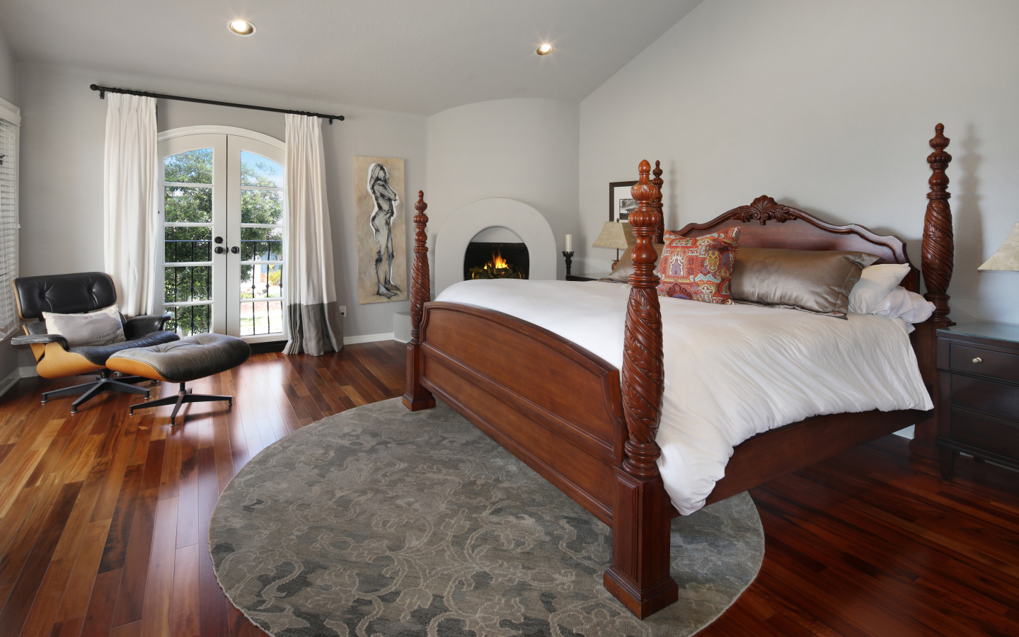 Большая деревянная кровать в спальне с камином 