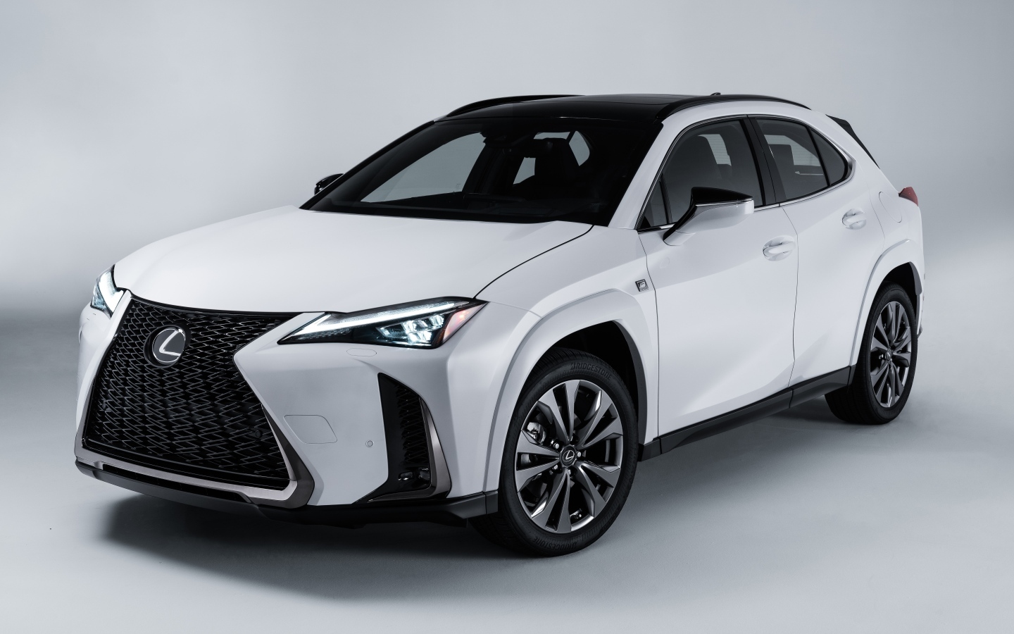 Белый автомобиль Lexus UX 250h AWD F SPORT, 2023 года на сером фоне