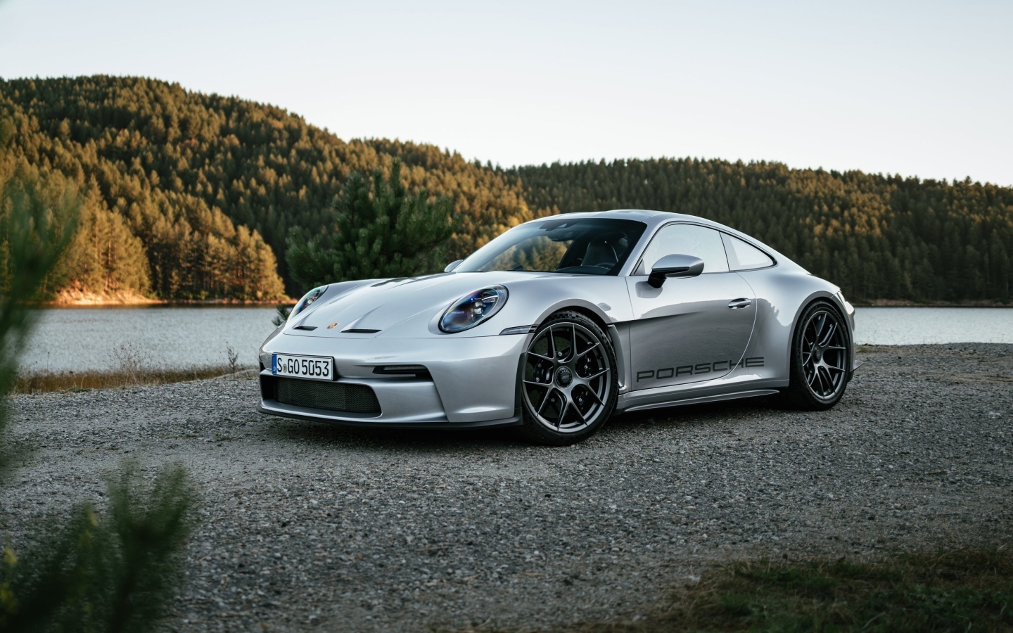 Серебристый автомобиль Porsche 911 ST 2023 года у воды