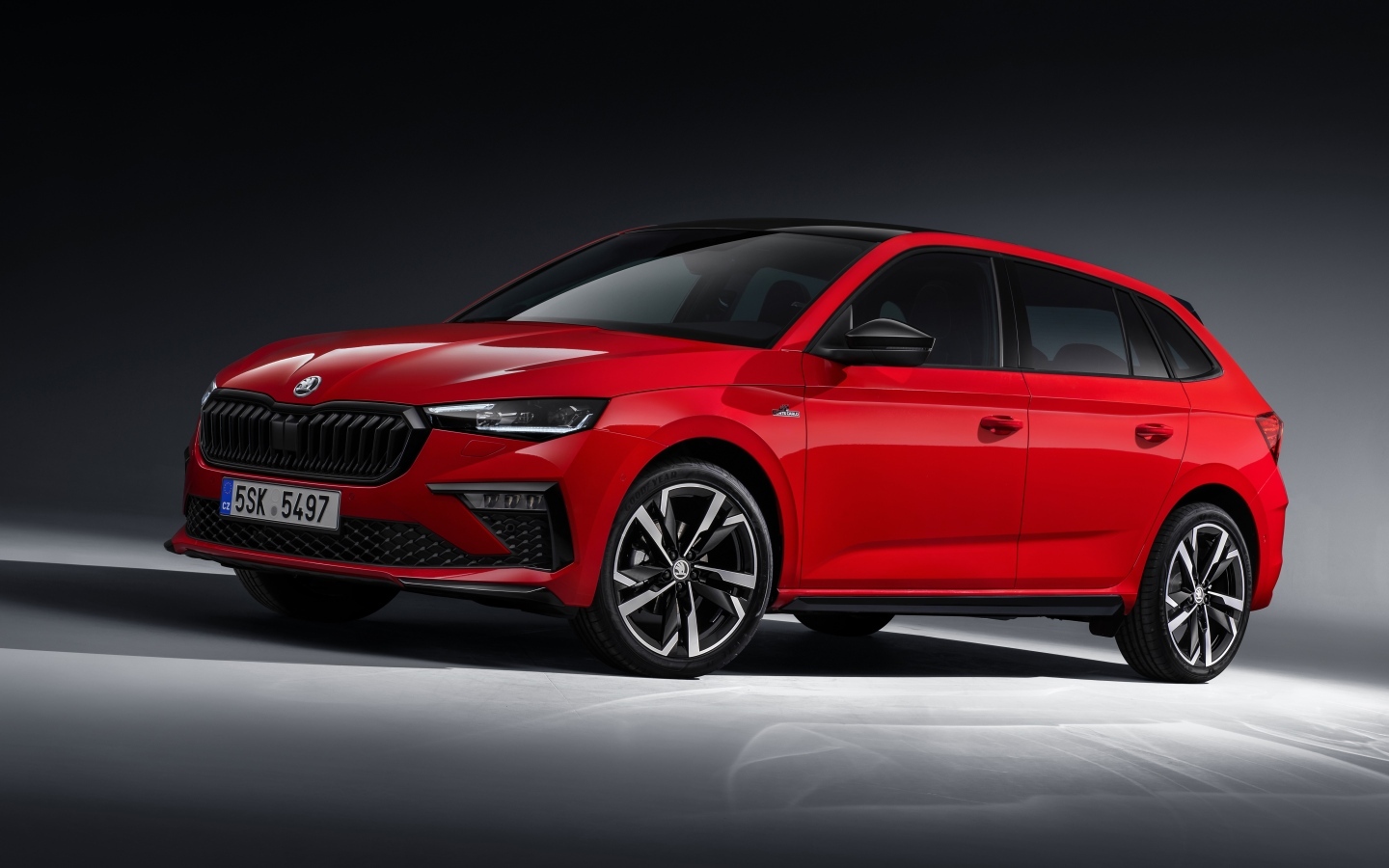 Красный автомобиль Skoda Scala Monte Carlo 2023 года на сером фоне
