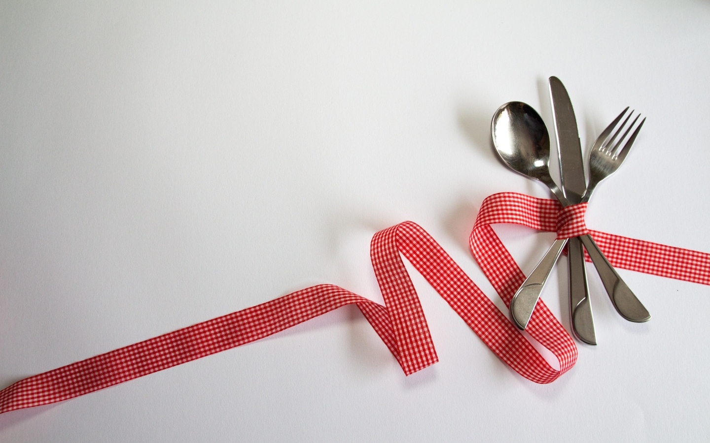 Столовые приборы перевязаны лентой на сером фоне