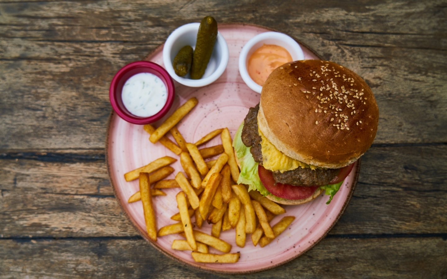 Гамбургер на тарелке с картофелем фри, огурцами и соусом