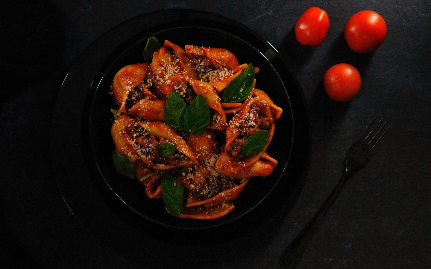 Большие макароны с фаршем в черной тарелке