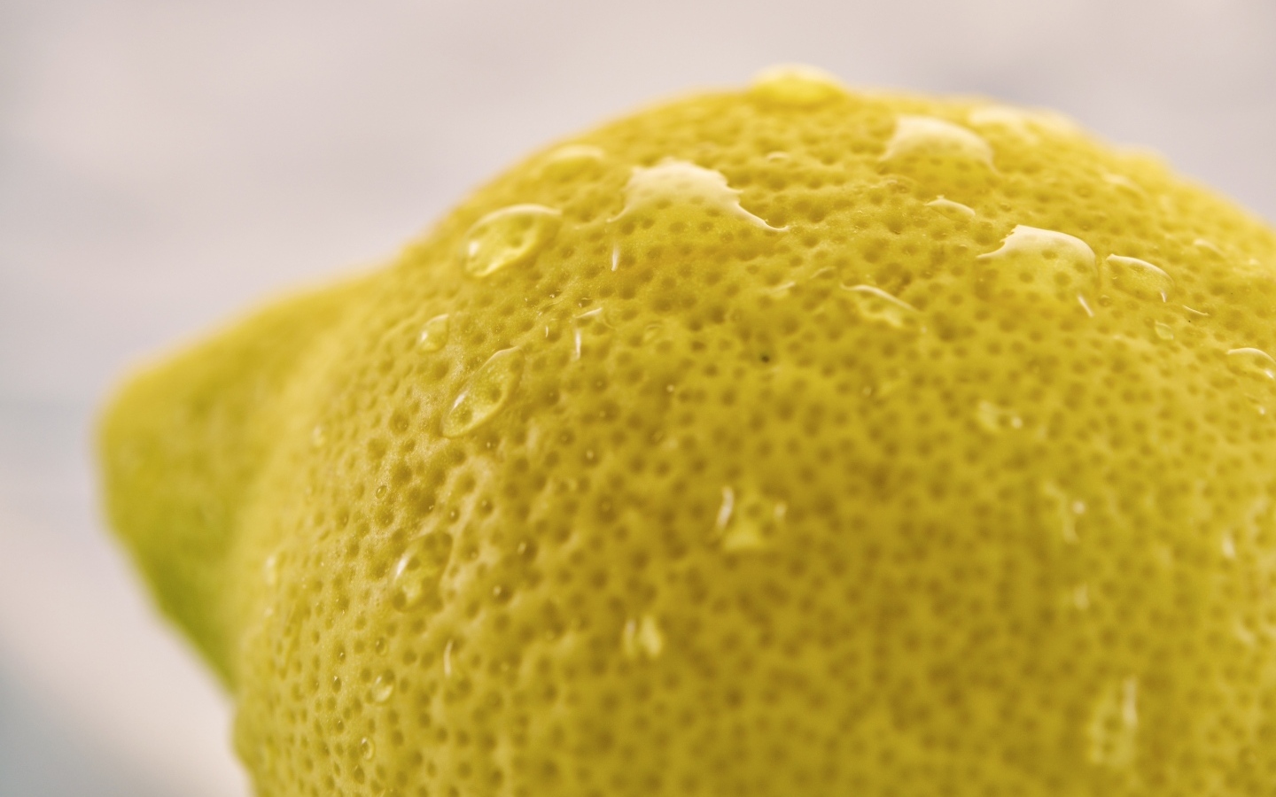 Большой желтый лимон в каплях воды крупным планом