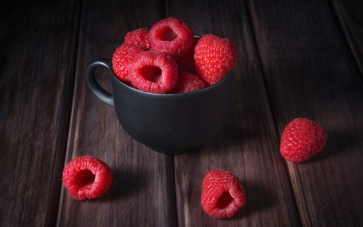 Черная чашка с красными ягодами малины