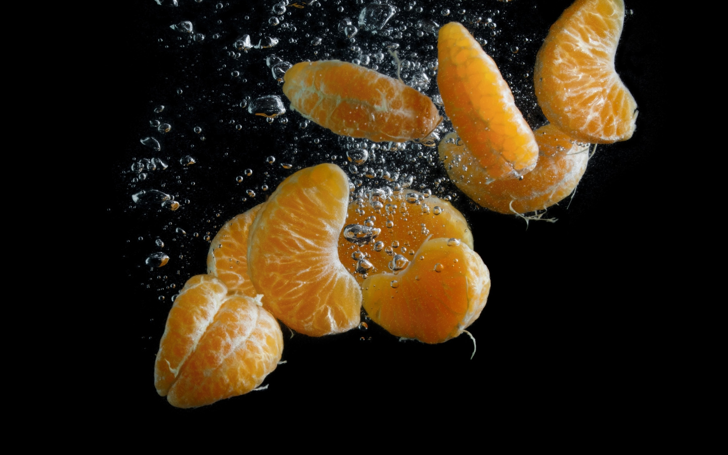 Дольки мандарина в воде на черном фоне