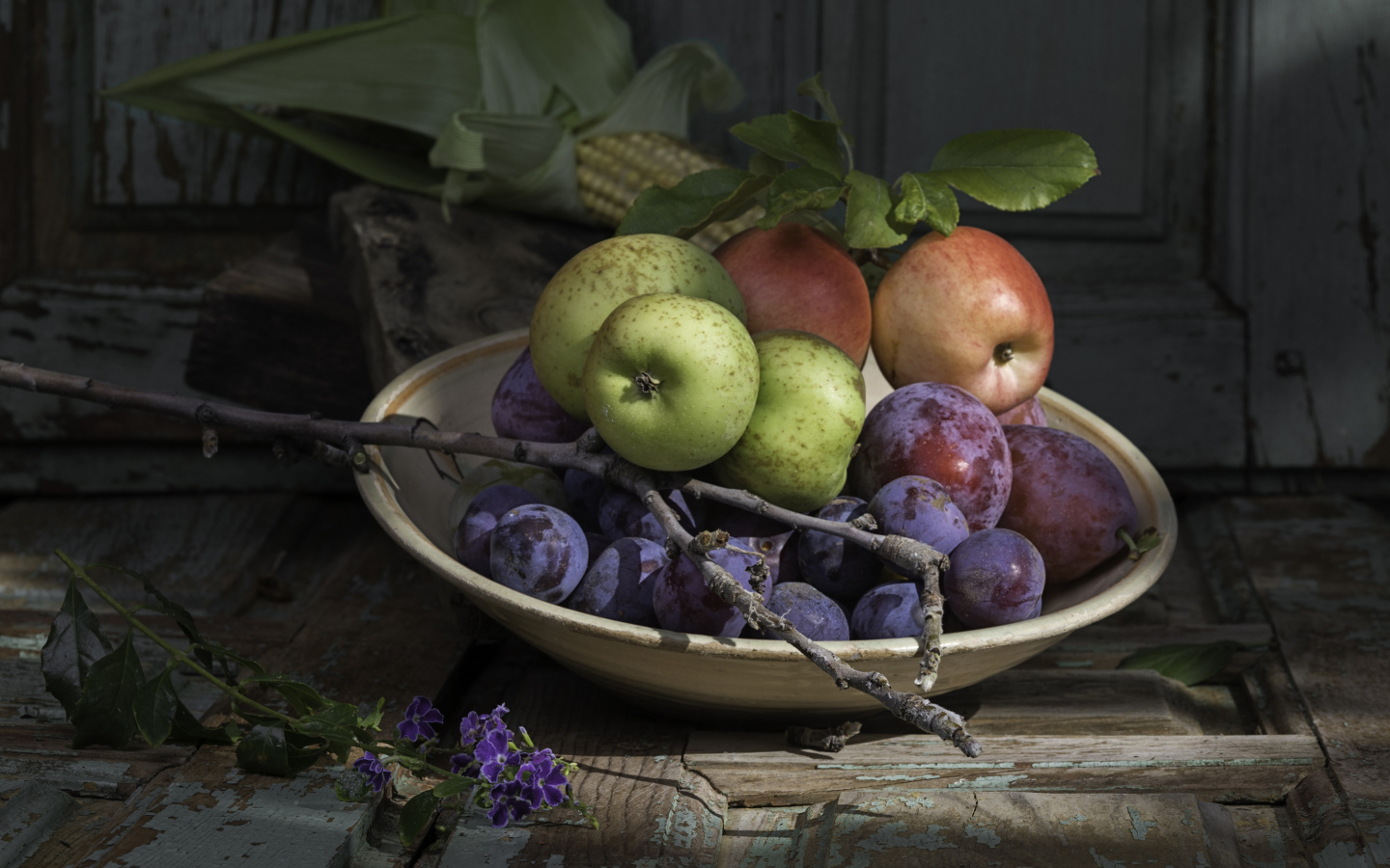 Спелые сливы на тарелке с яблоками