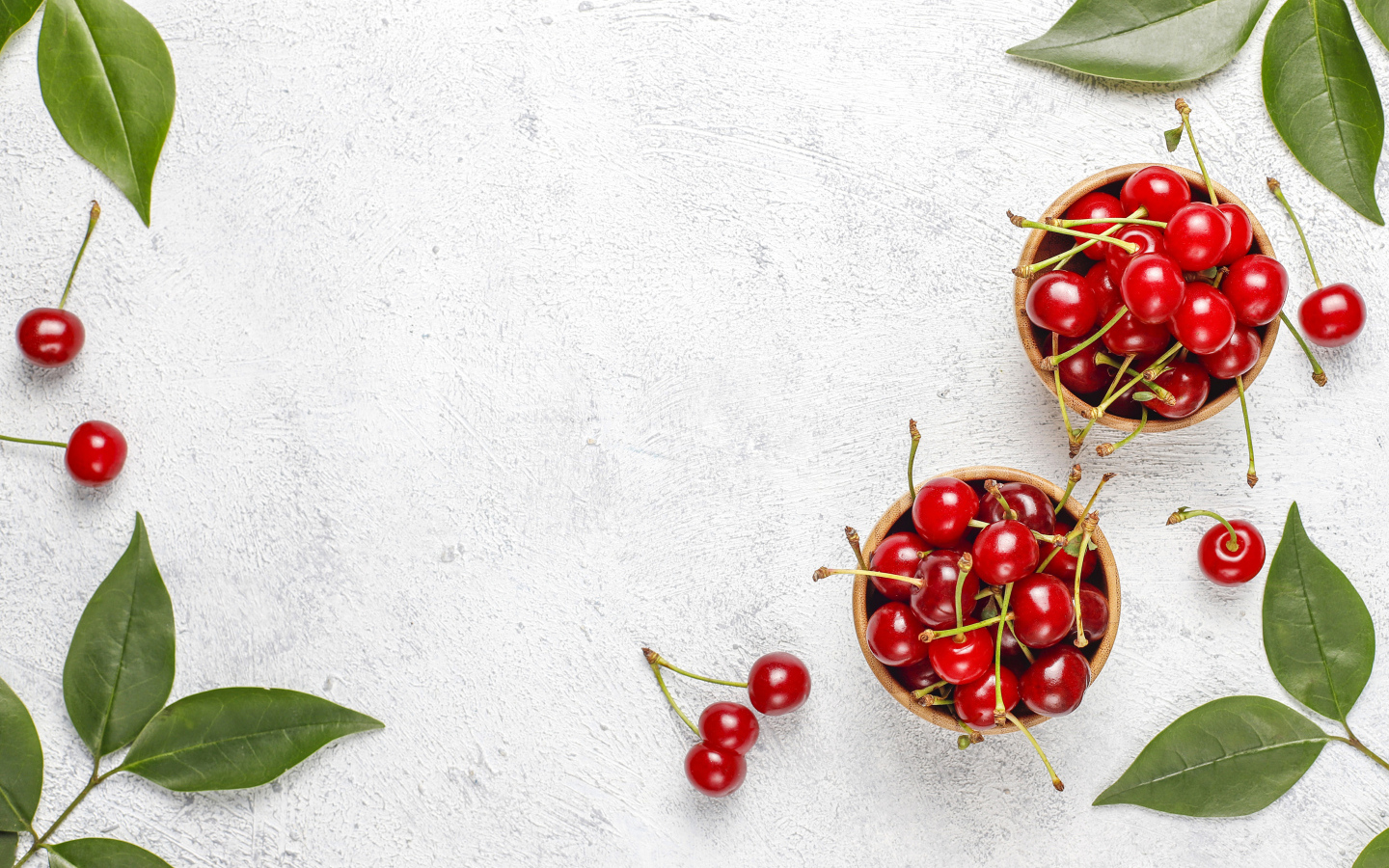 Спелая красная вишня с зелеными листьями на столе