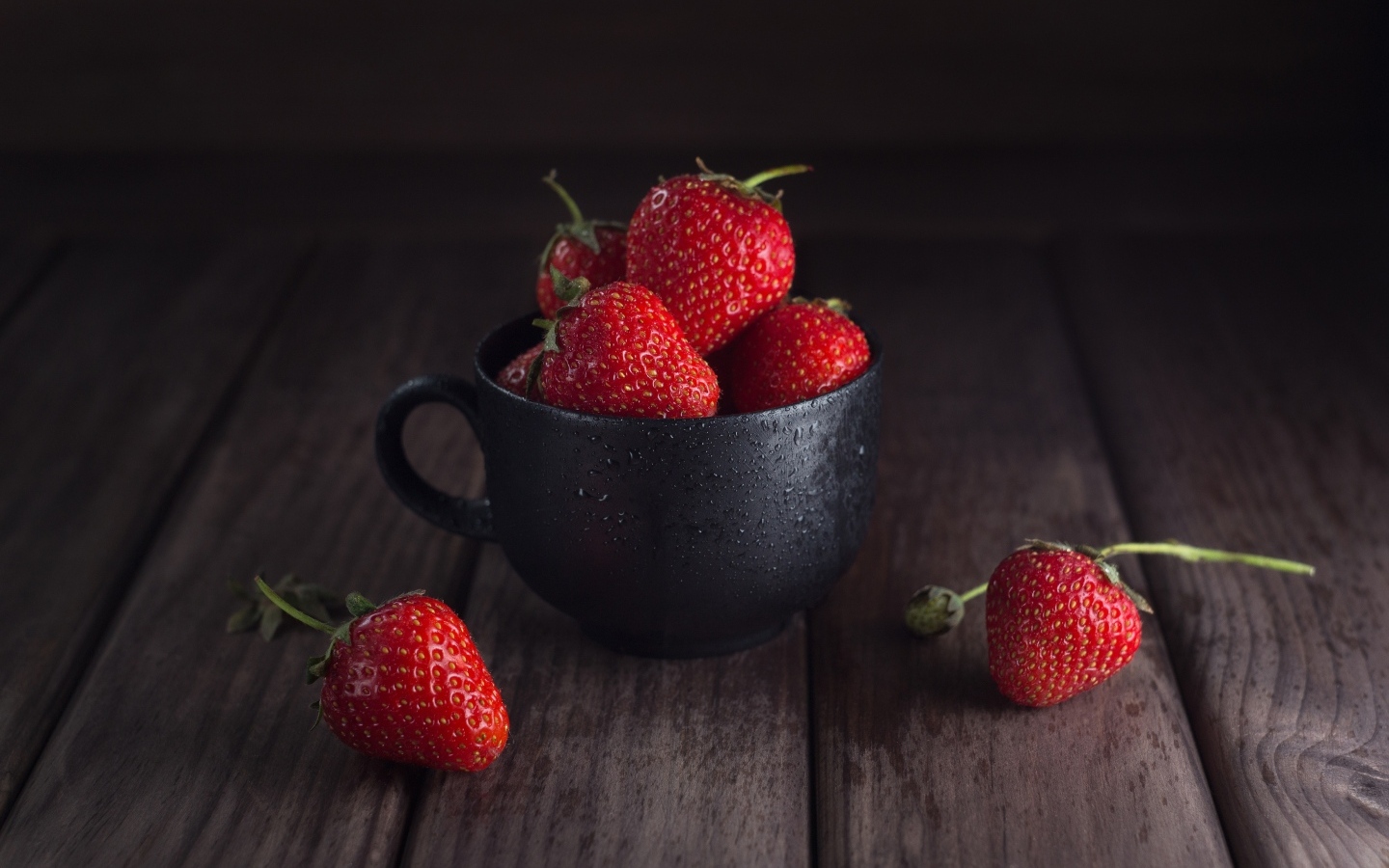Черная чашка с красными ягодами клубники