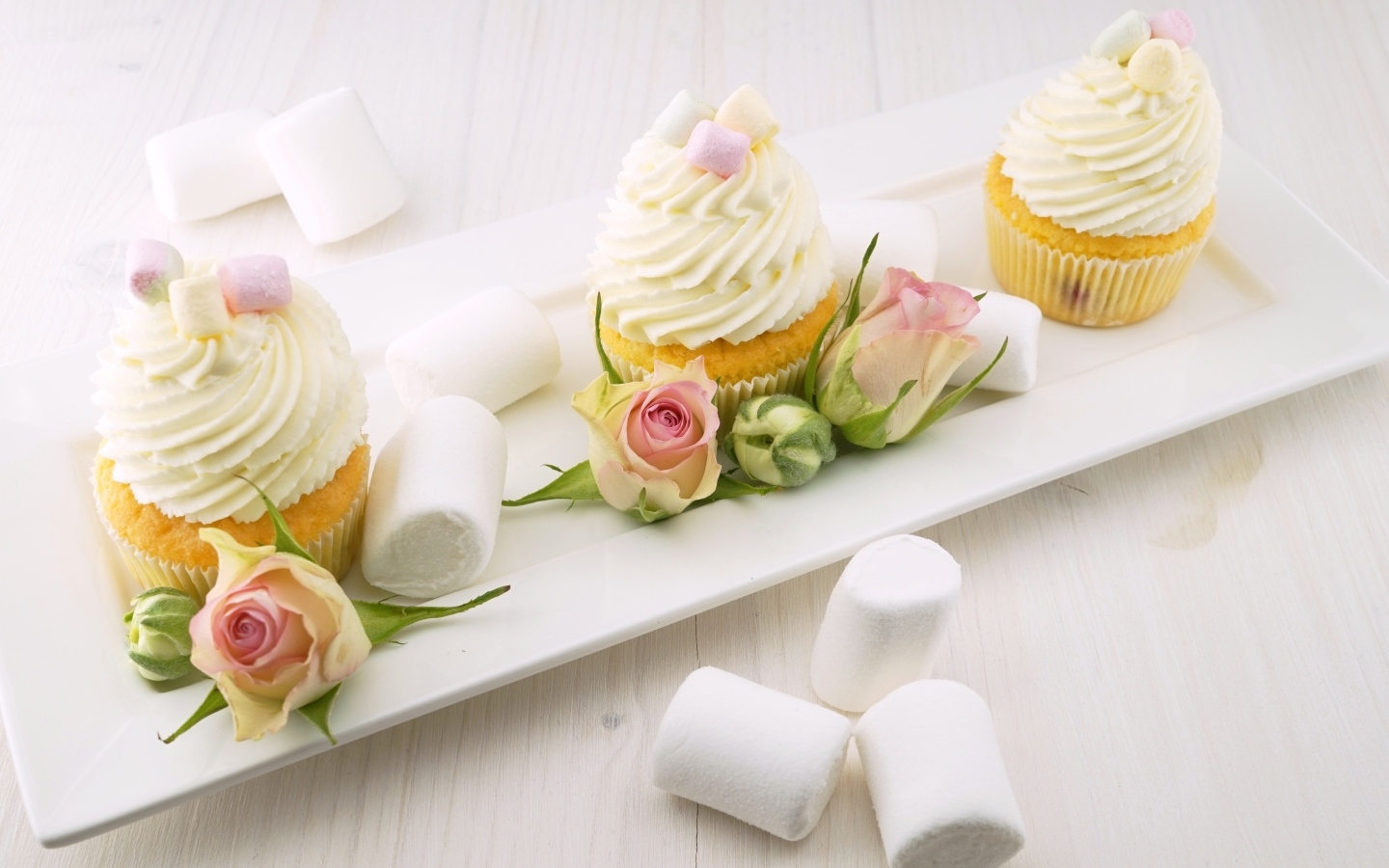 Капкейки с кремом на тарелке с розами и маршмеллоу