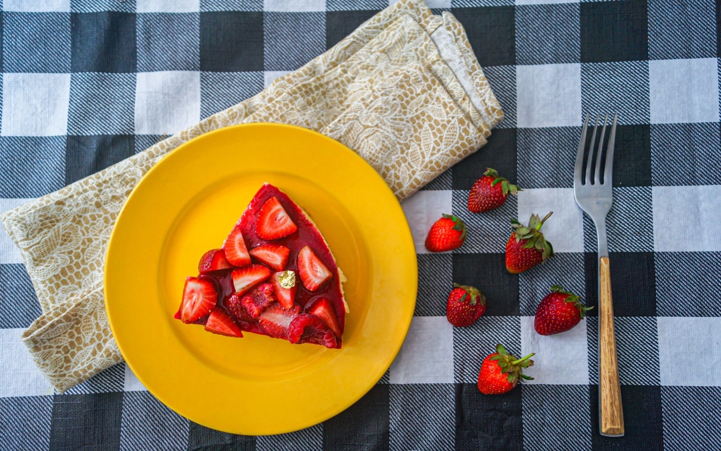 Кусок чизкейка с клубникой на желтой тарелке 