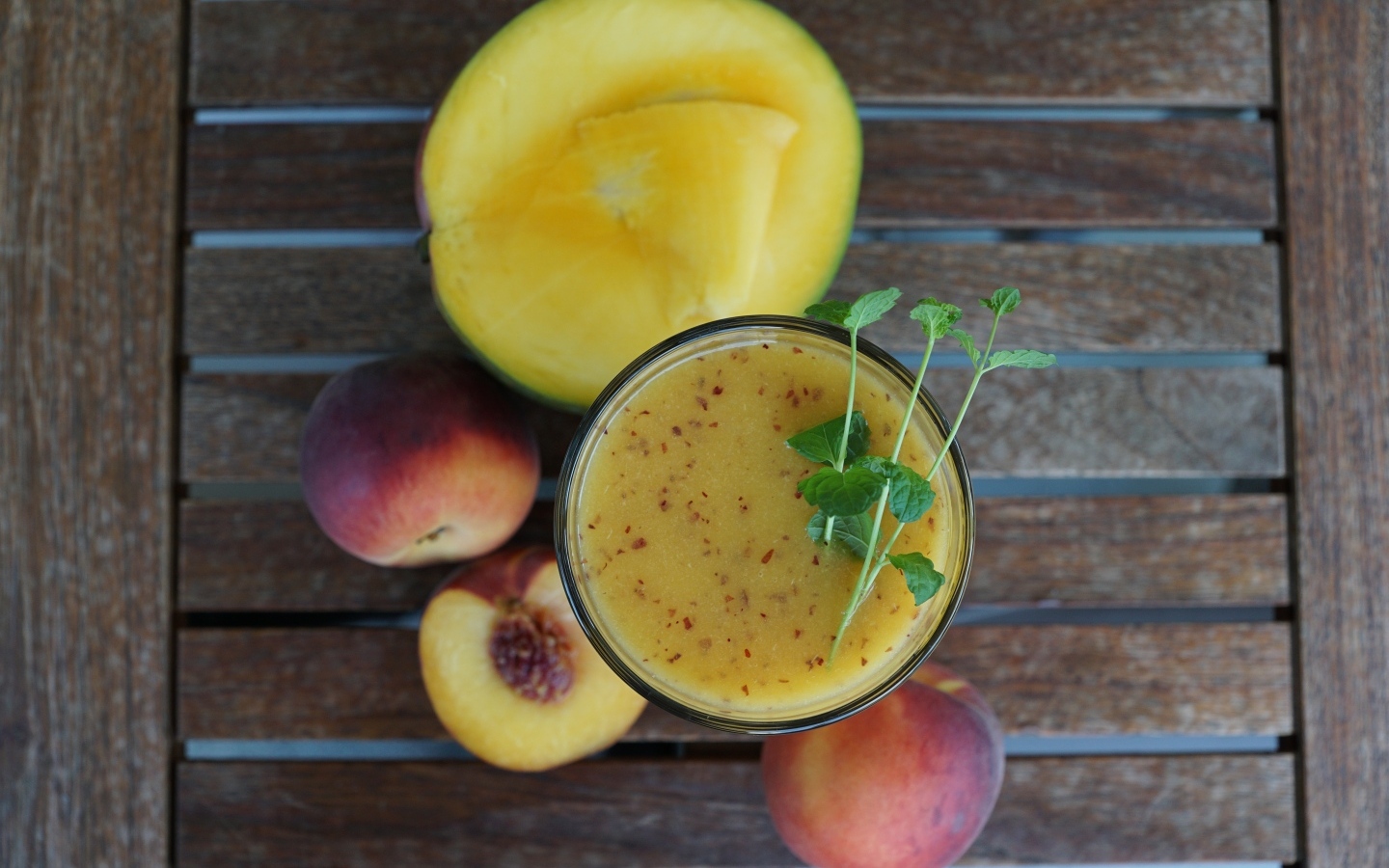 Коктейль с веточкой мяты на столе с фруктами