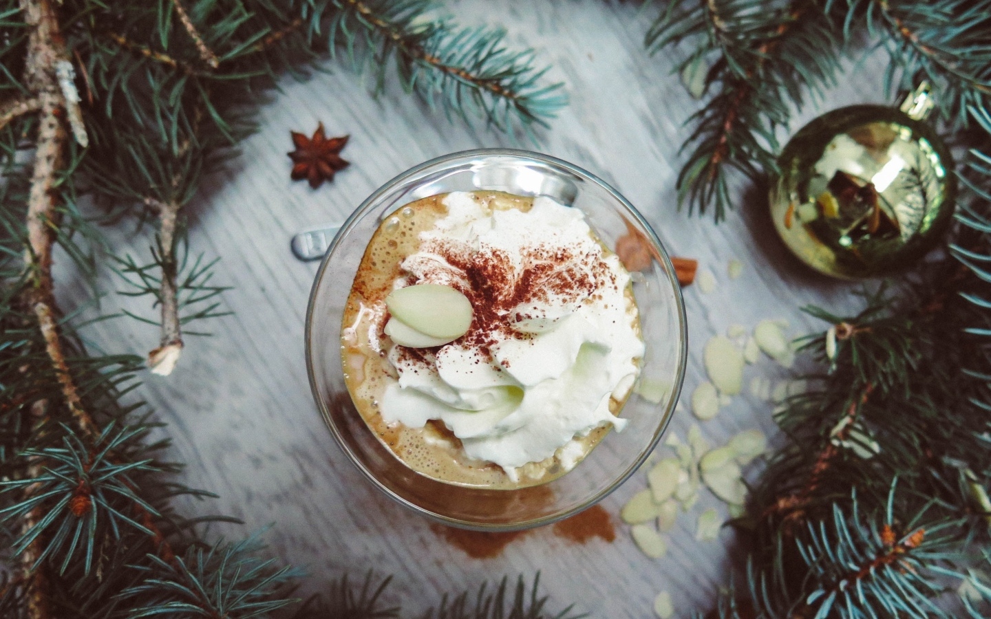 Горячий кофе с взбитыми сливками в чашке на столе с еловыми ветками