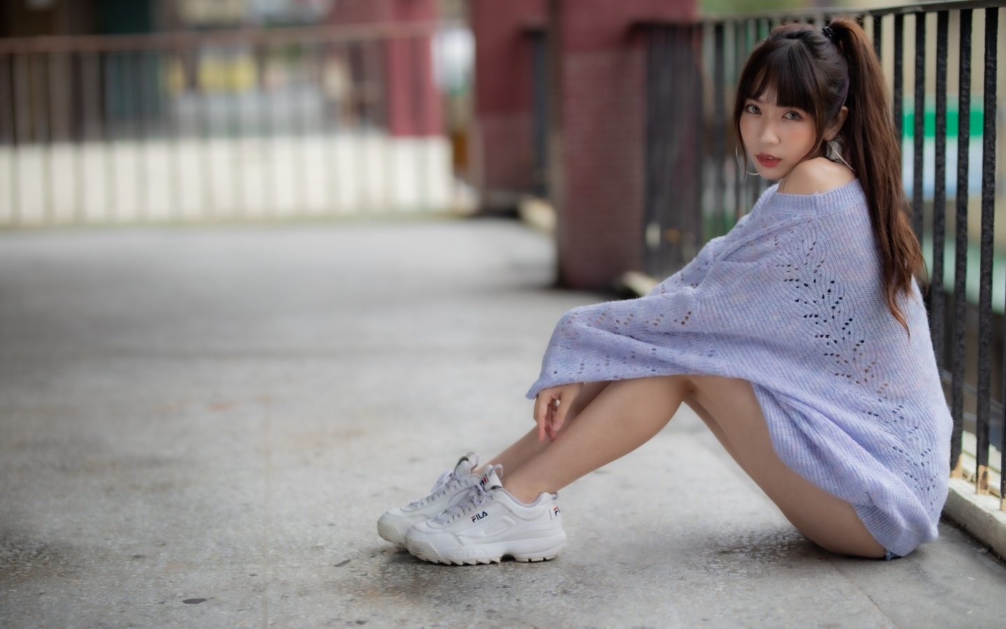 Девушка азиатка в свитере и белых кроссовках 