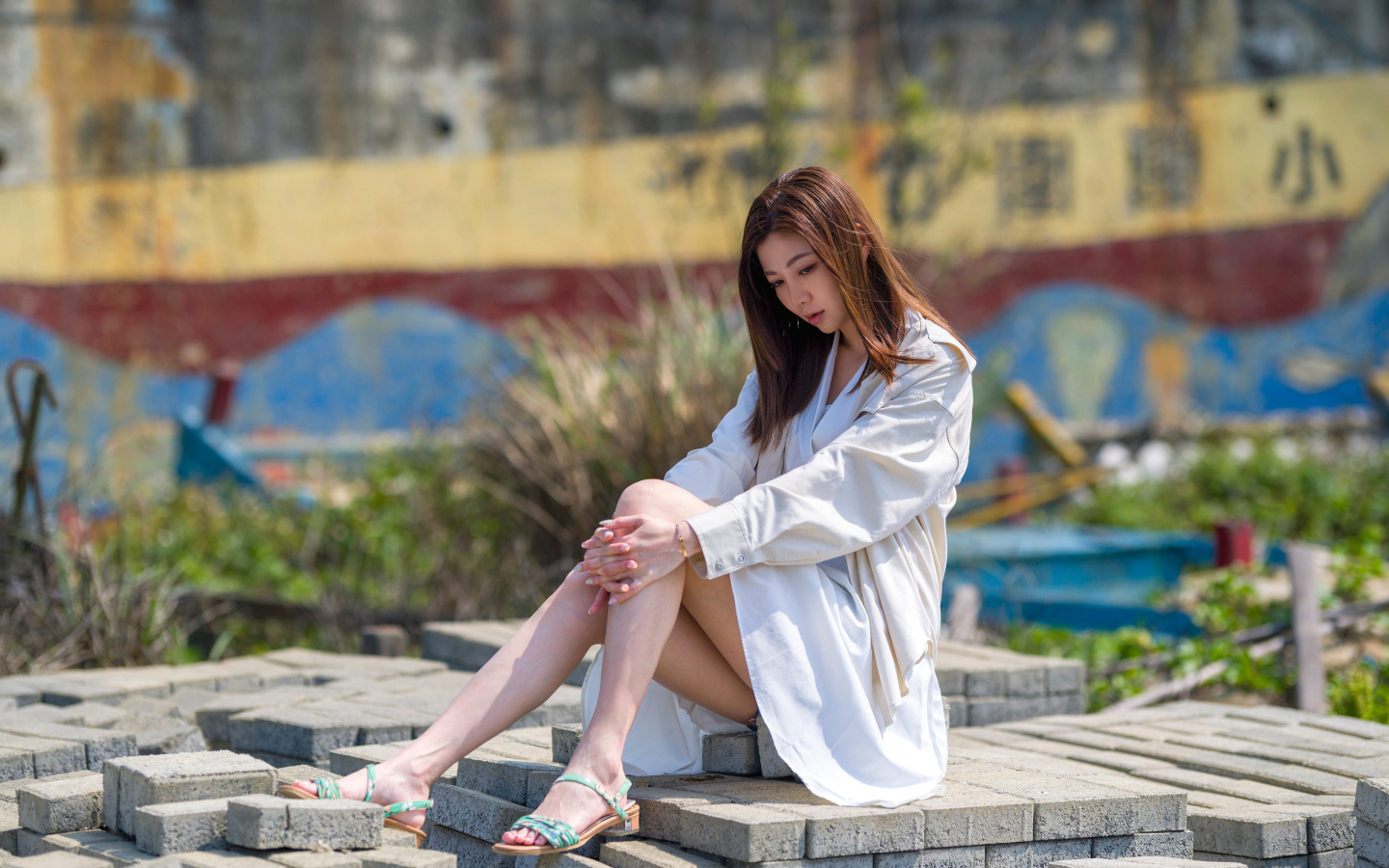 Девушка азиатка в белой рубашке сидит у воды