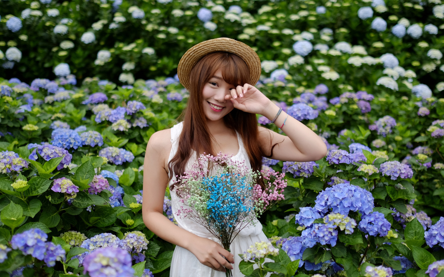 Девушка азиатка у куста с цветами гортензии