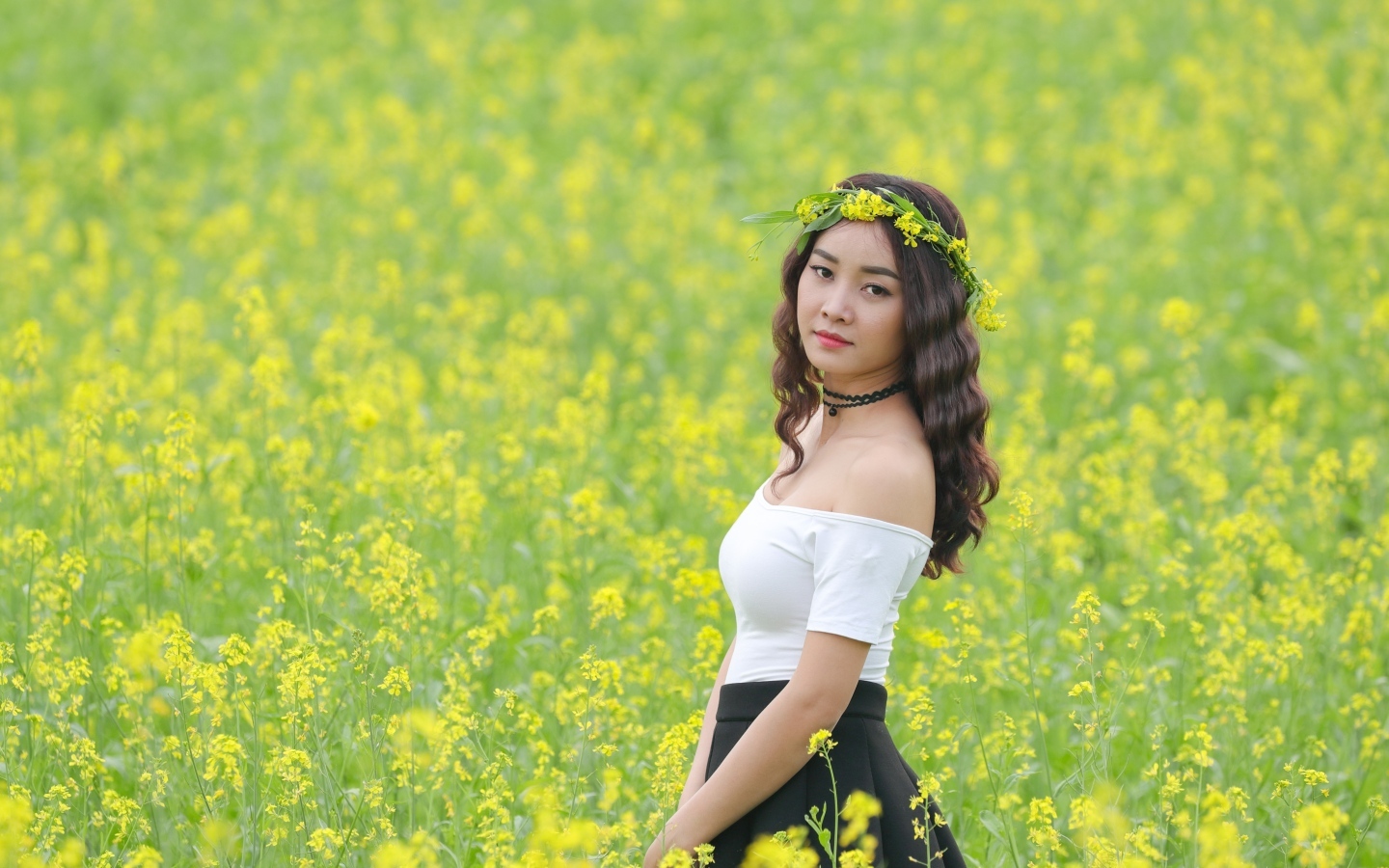 Девушка азиатка стоит на рапсовом поле
