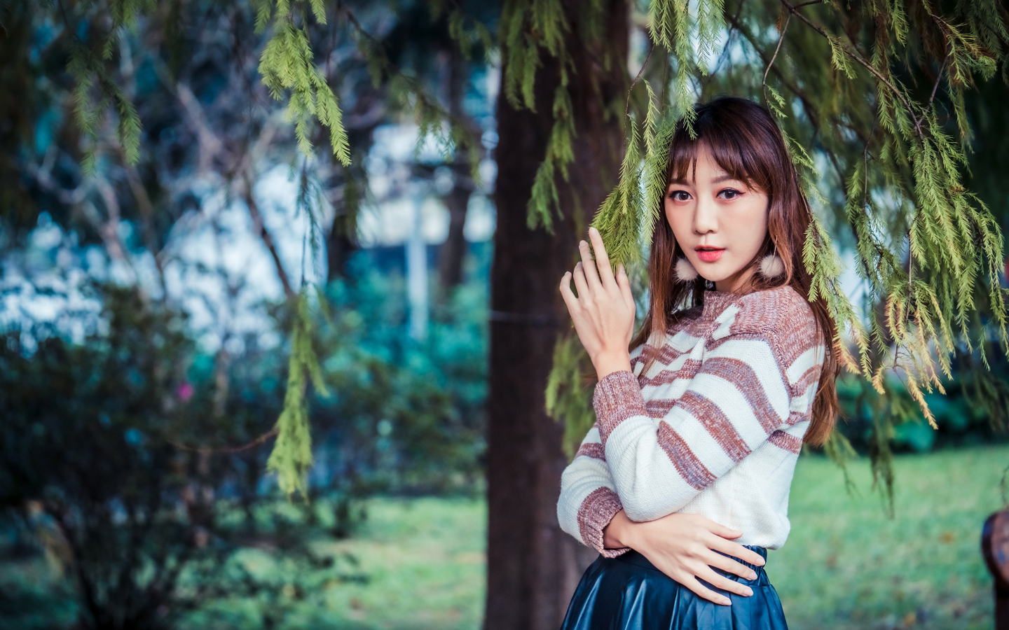 Девушка азиатка стоит у дерева ели