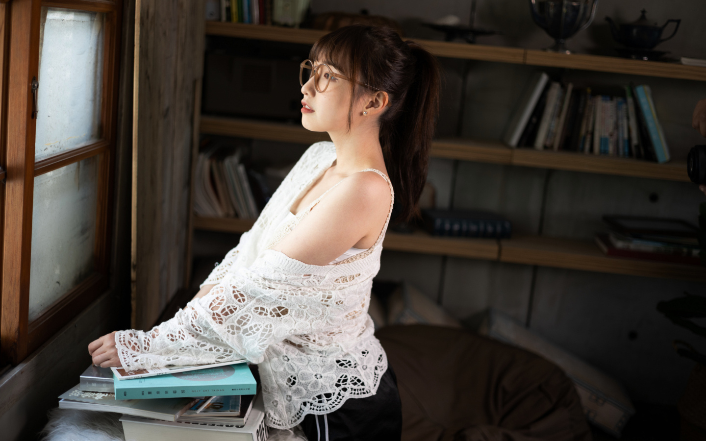 Девушка азиатка с книгами у окна