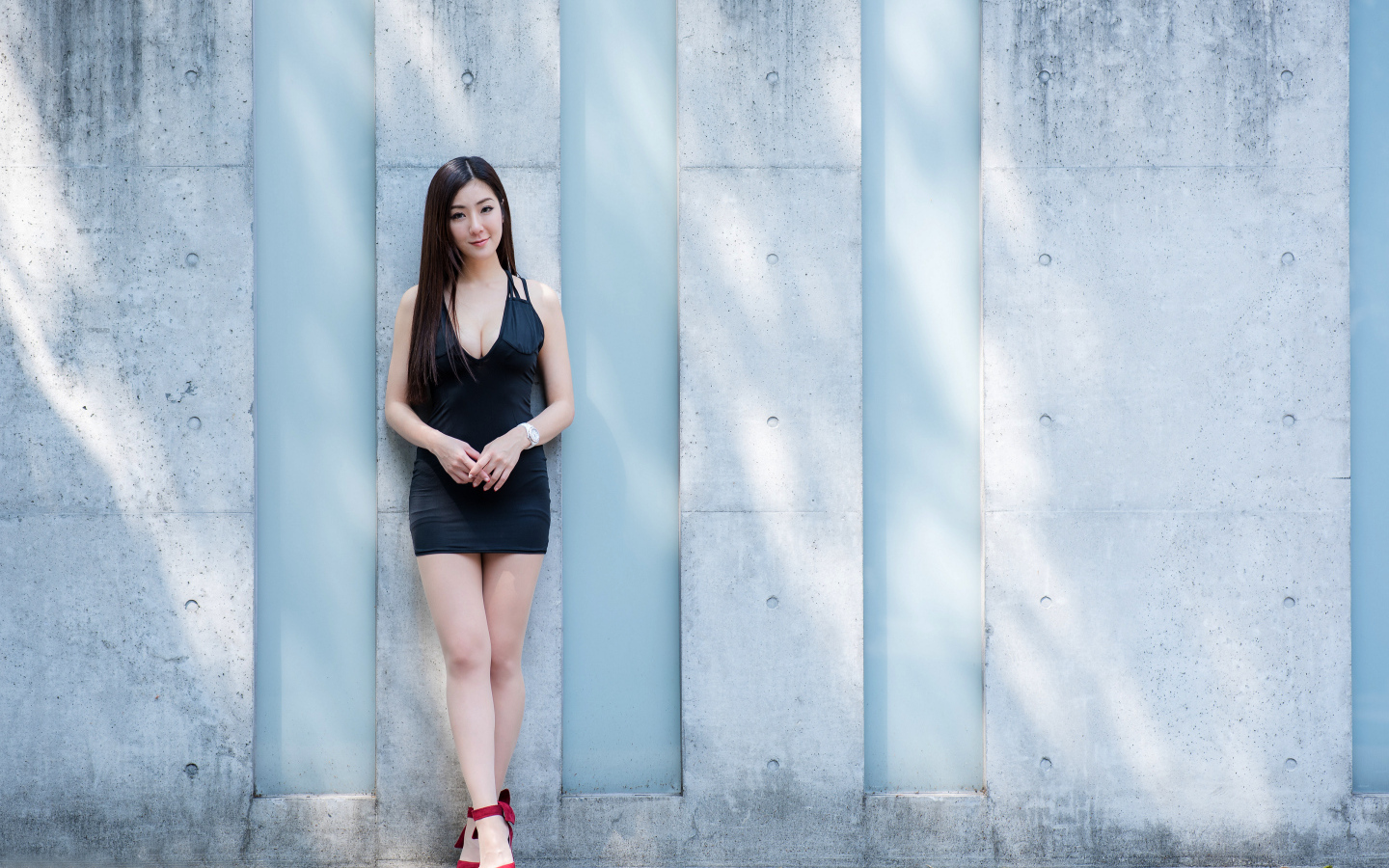 Красивая азиатка в коротком платье стоит у стены
