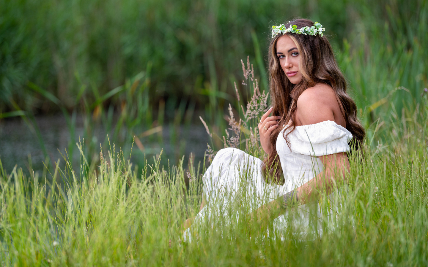 Красивая девушка в белом платье с венком на голове у пруда 