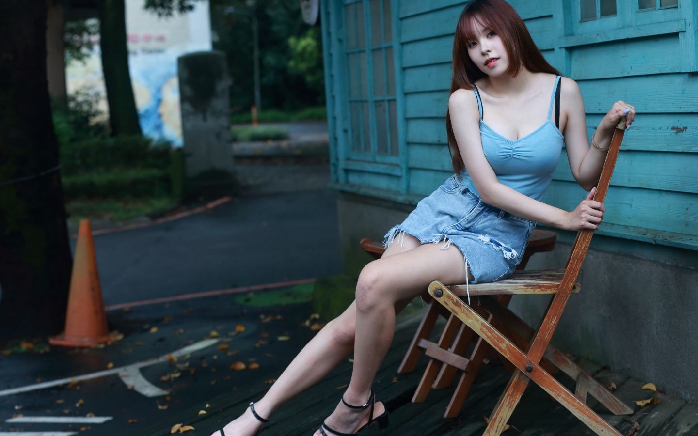 Красивая девушка сидит на стуле у дома