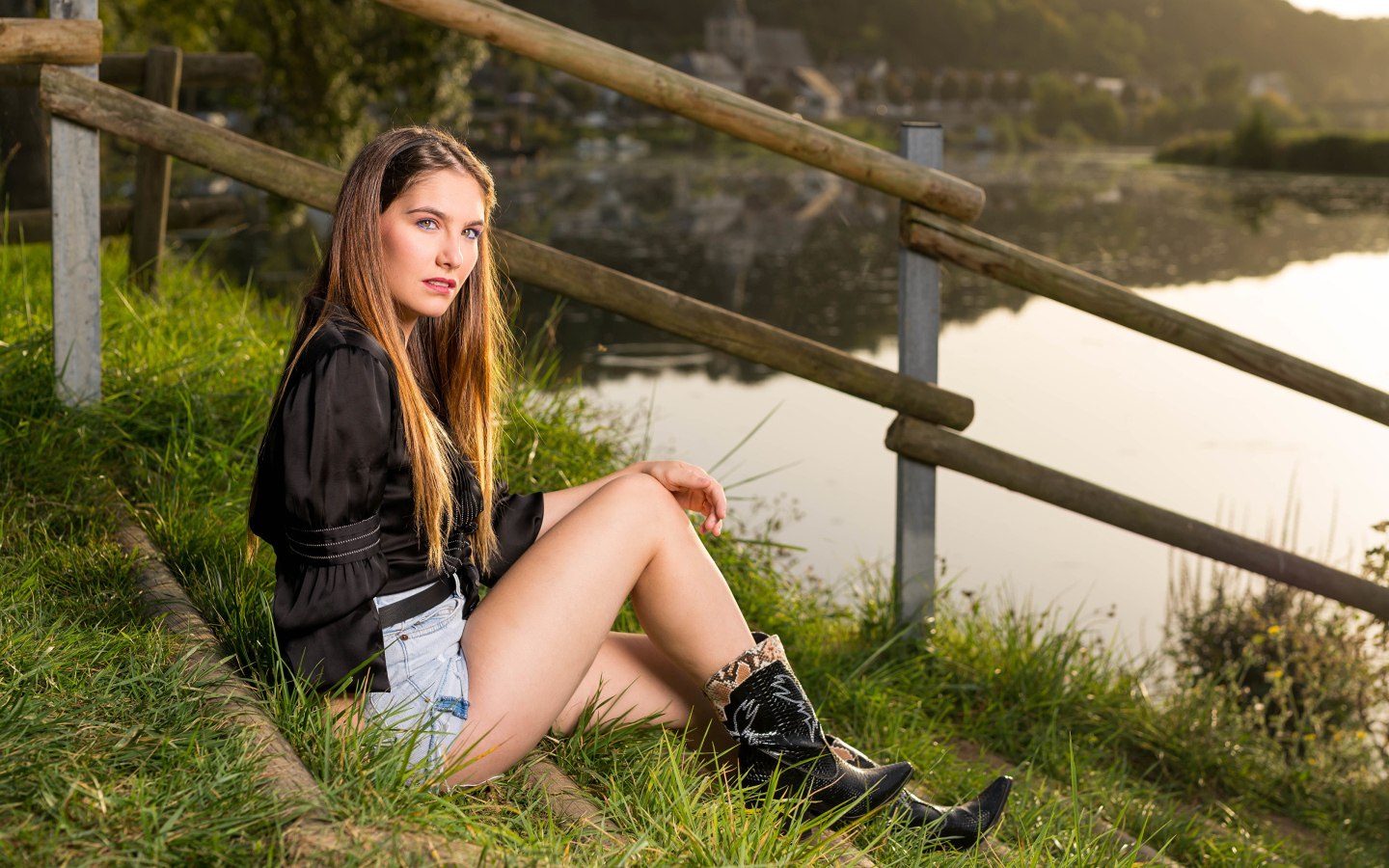 Красивая девушка сидит на берегу реки