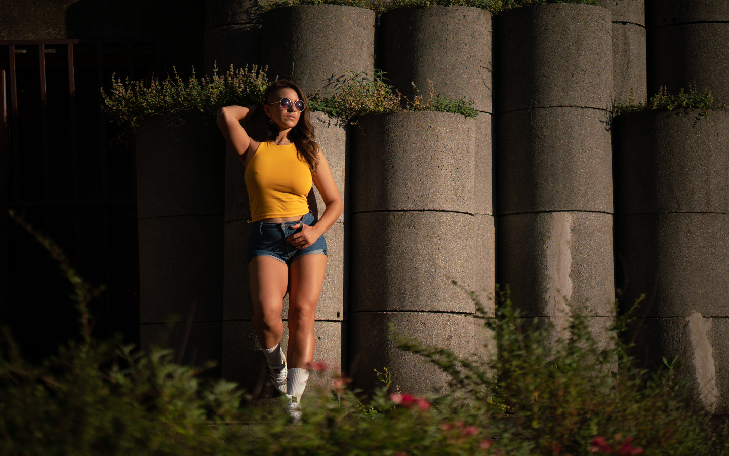 Красивая девушка в очках стоит у стены