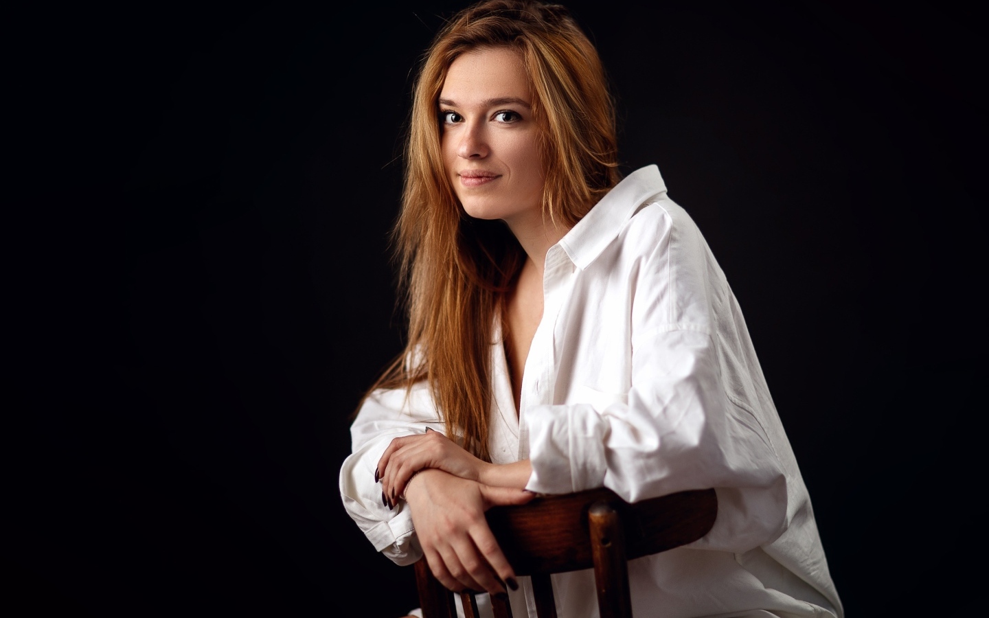 Милая девушка в белой рубашке сидит на стуле