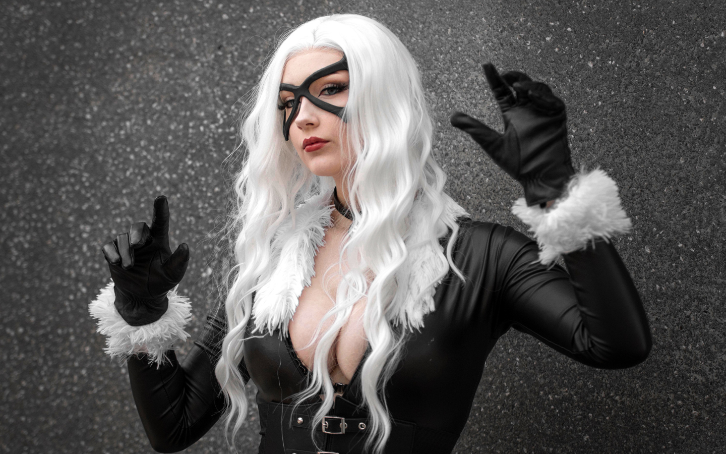 Девушка в белом парике в черном костюме у серой стены