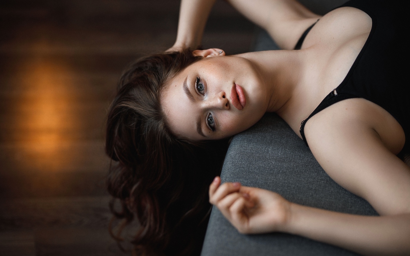 Девушка с длинными волосами лежит  на кровати