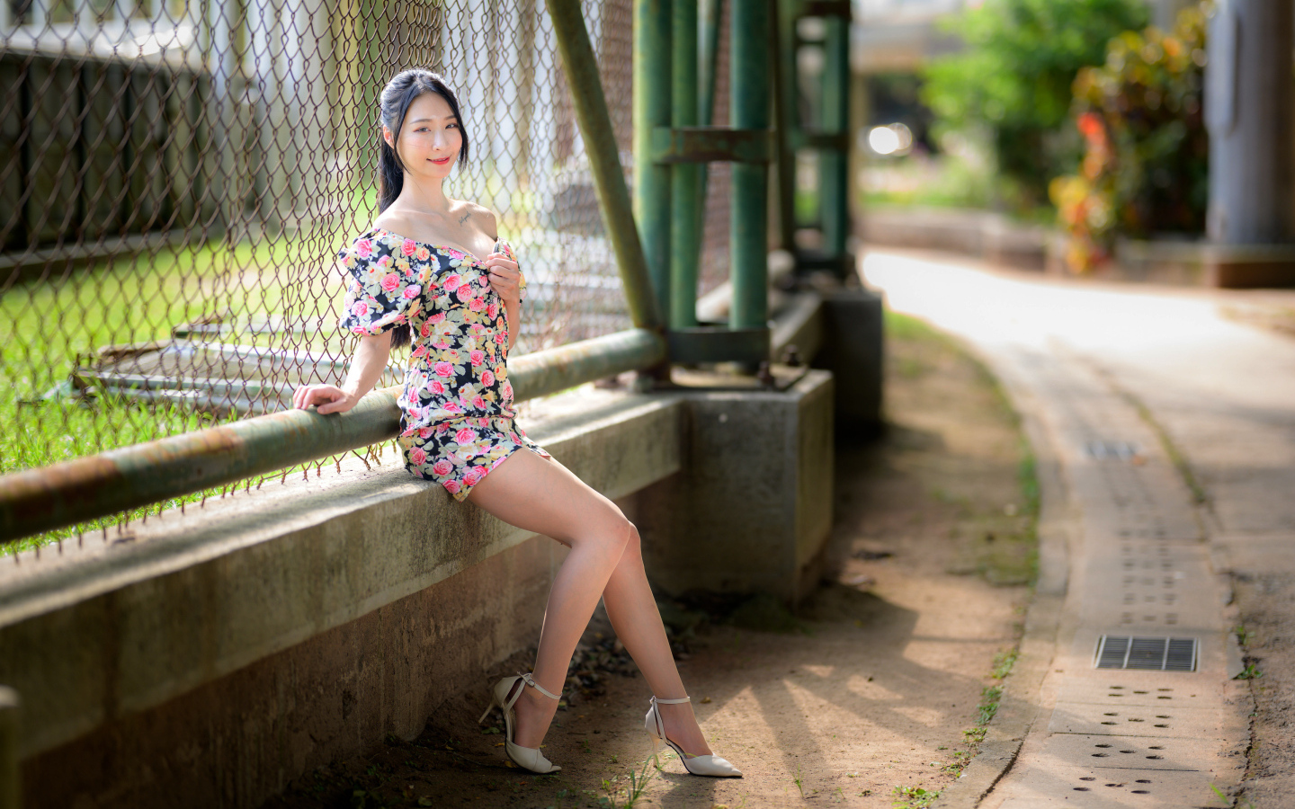 Улыбающаяся азиатка сидит у забора