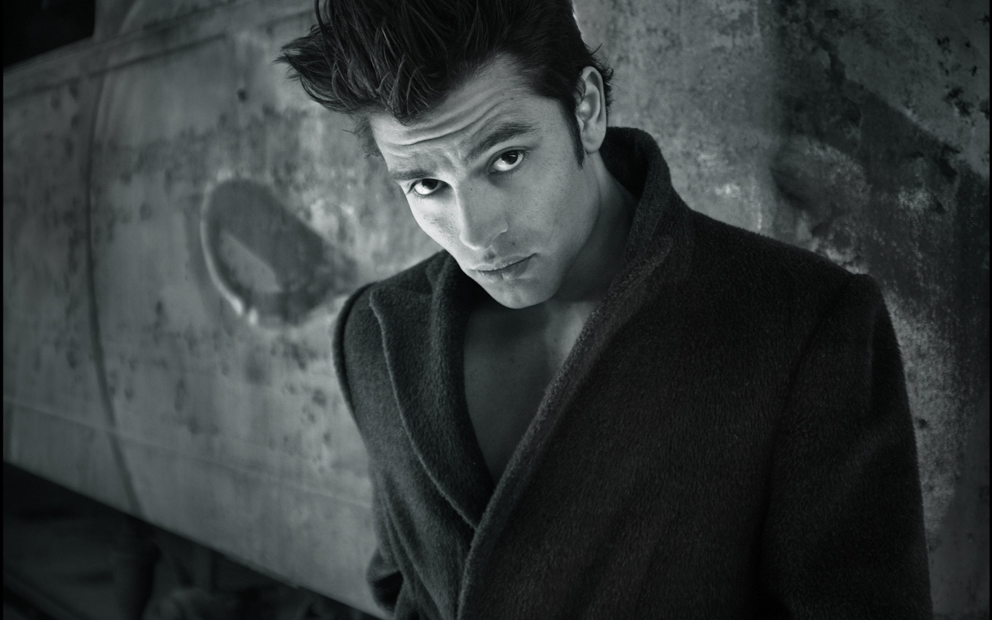 Красивый мужчина в черном пальто у стены