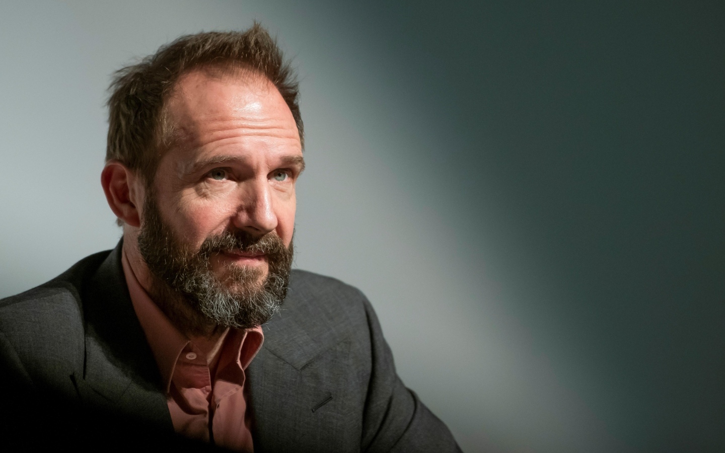 Актер Рэйф Файнс с бородой на сером фоне