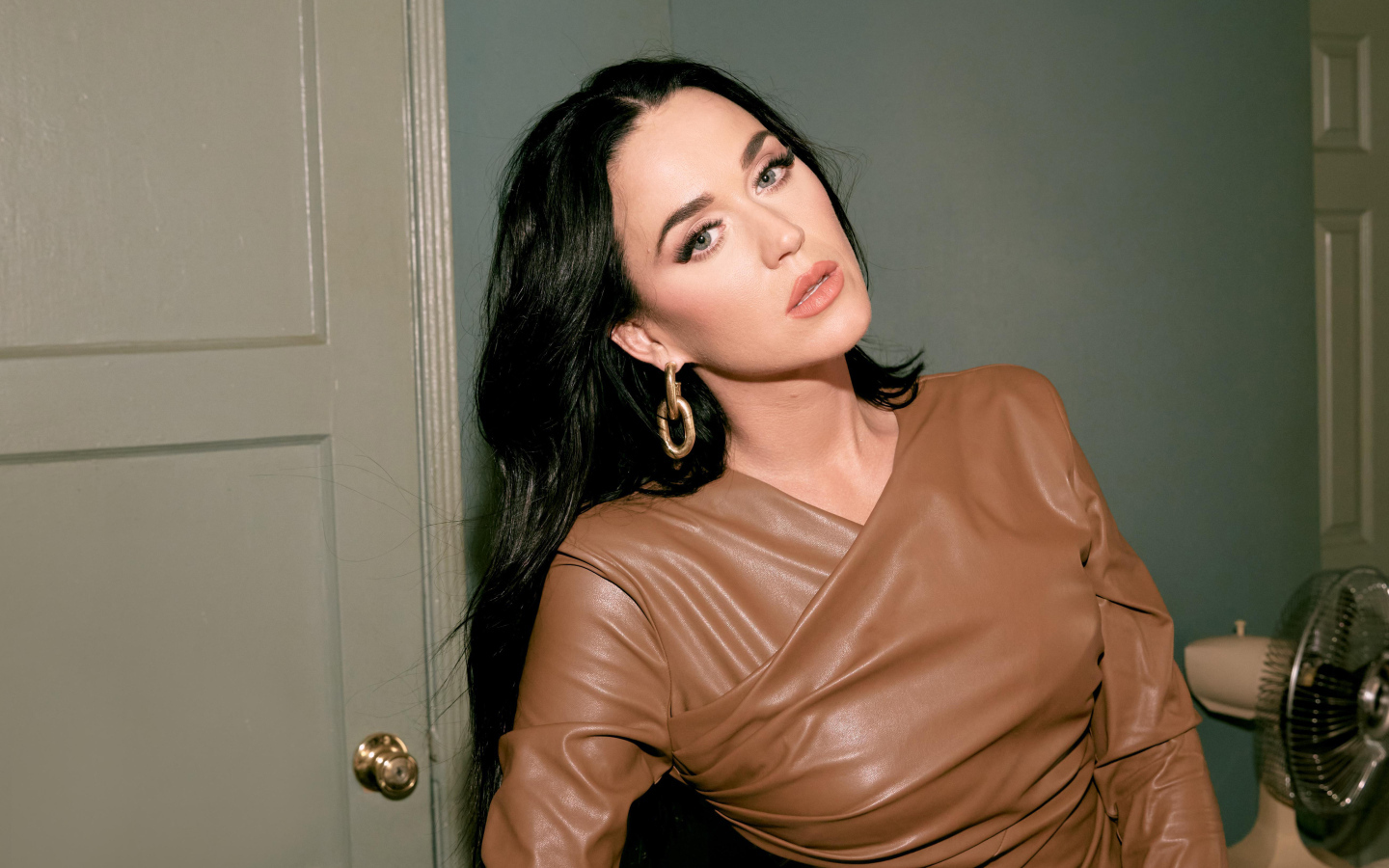 Длинноволосая брюнетка Кэти Перри стоит в комнате у двери