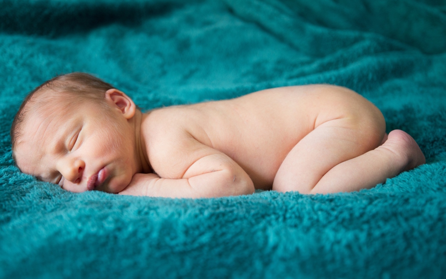 Грудной ребенок спит на синем пледе