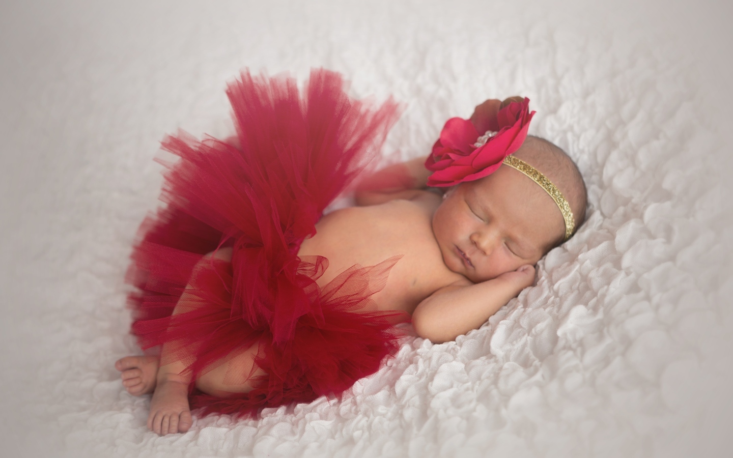 Красивая пышная красная юбка и бант на спящей малышке