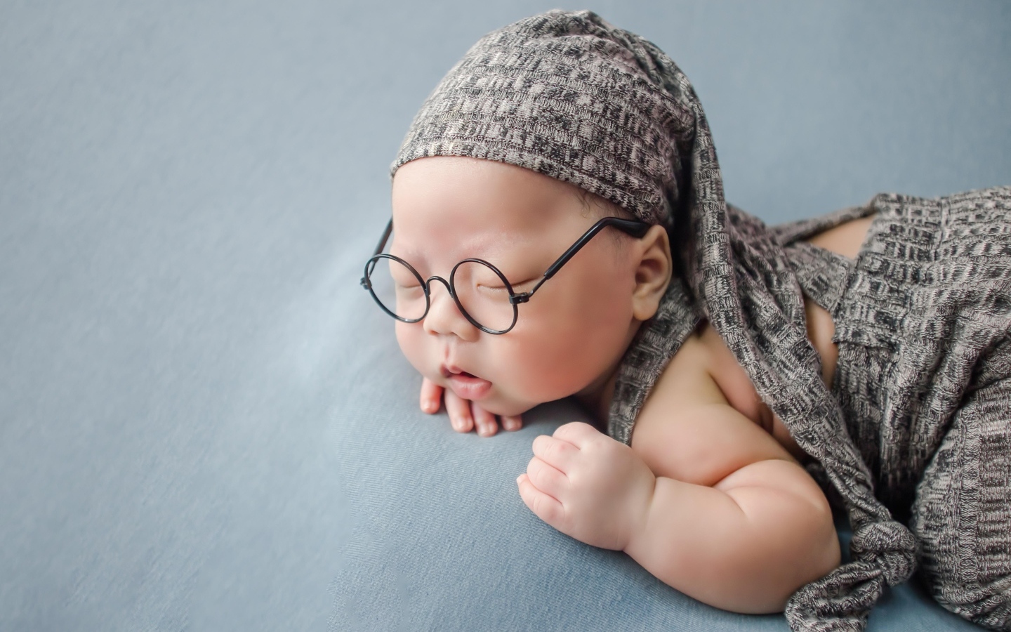 Забавный малыш в очках одет в серый костюм