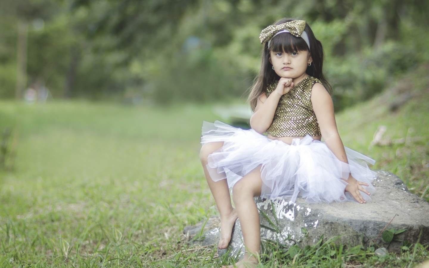 Девочка в красивом платье сидит на камне