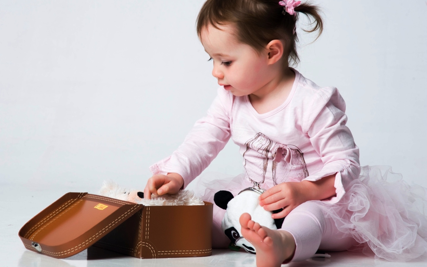 Девочка в розовом наряде с маленьким чемоданом