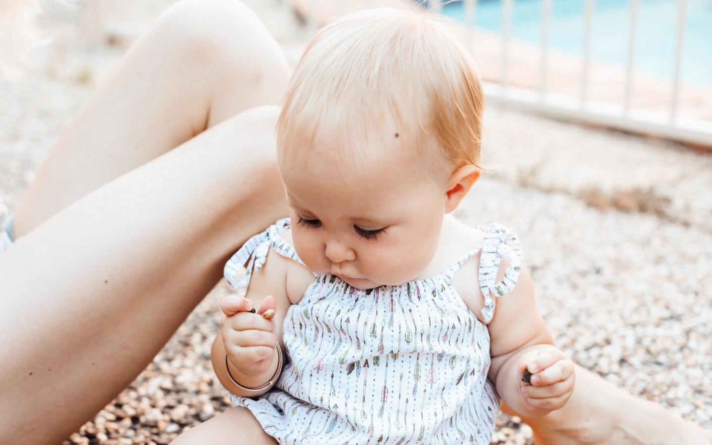 Маленькая светловолосая девочка сидит на песке