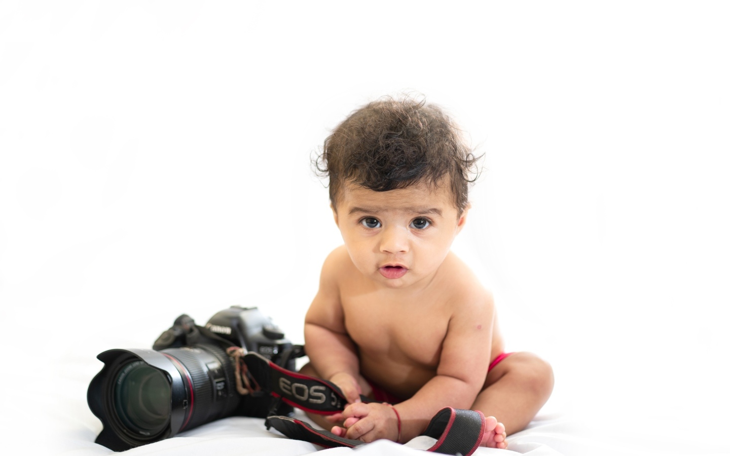Маленький мальчик с фотоаппаратом на белом фоне
