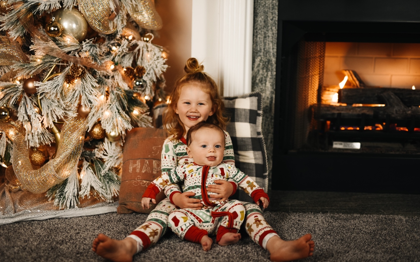 Маленькие брат и сестра сидят у новогодней ели