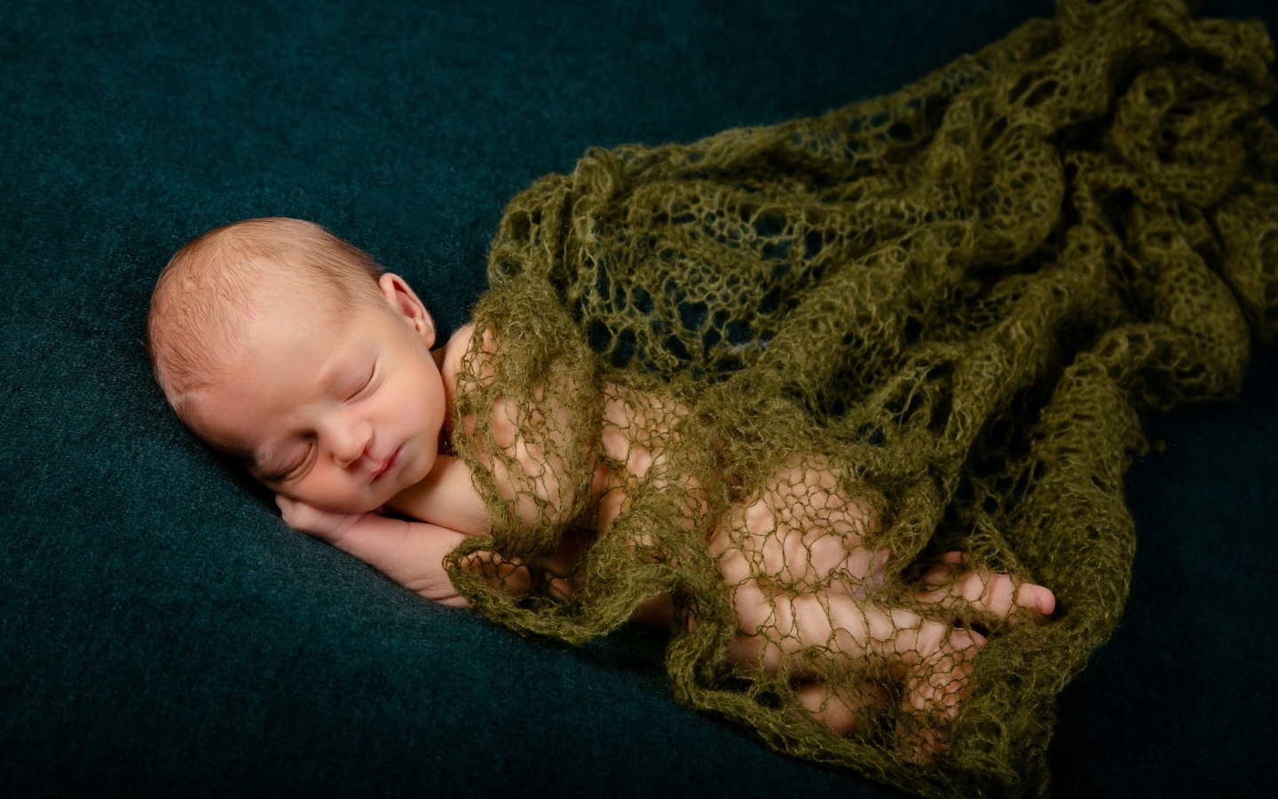 Спящий новорожденный ребенок укрыт шалью