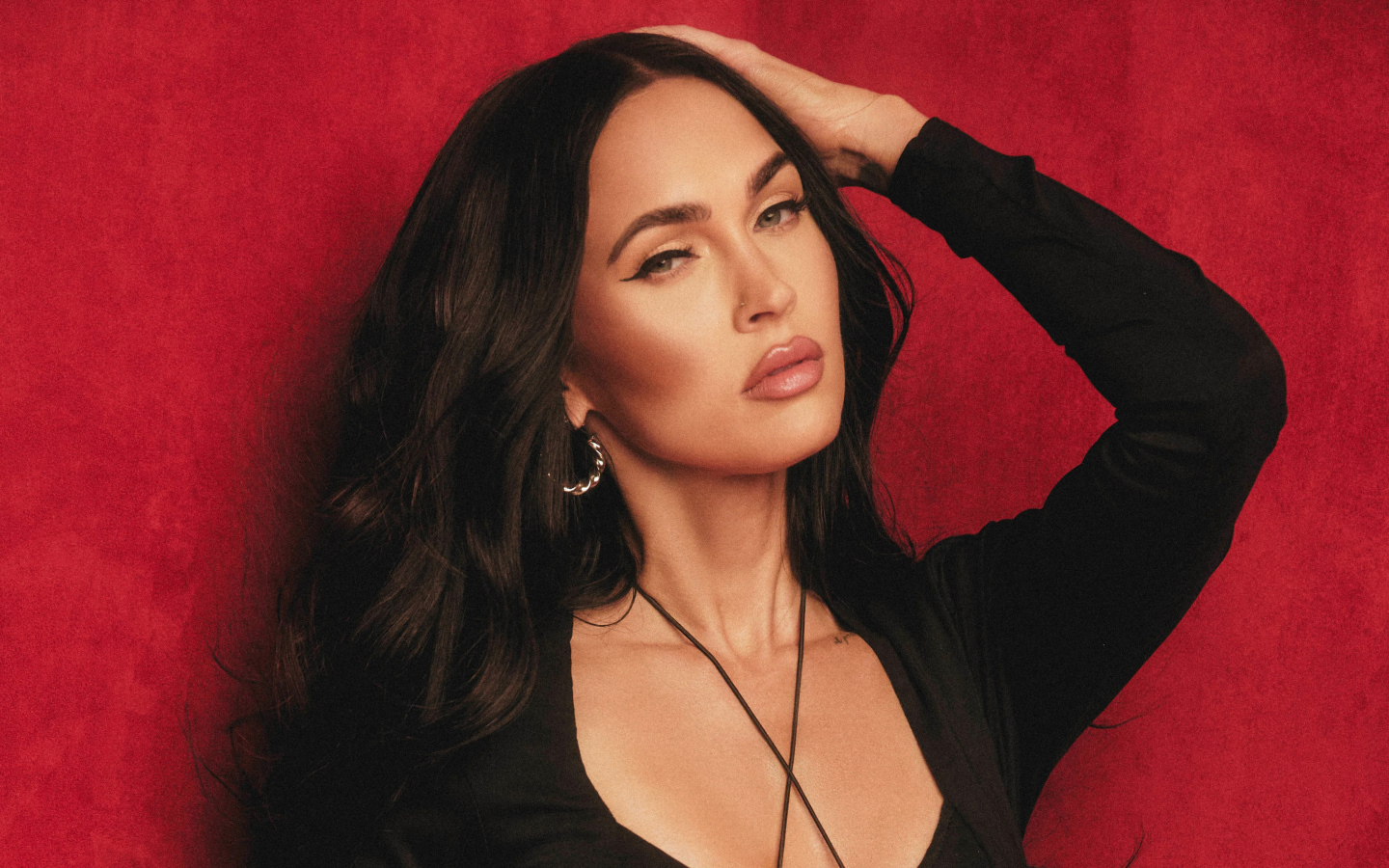 Красивая  Меган Фокс в черном платье у красной стены